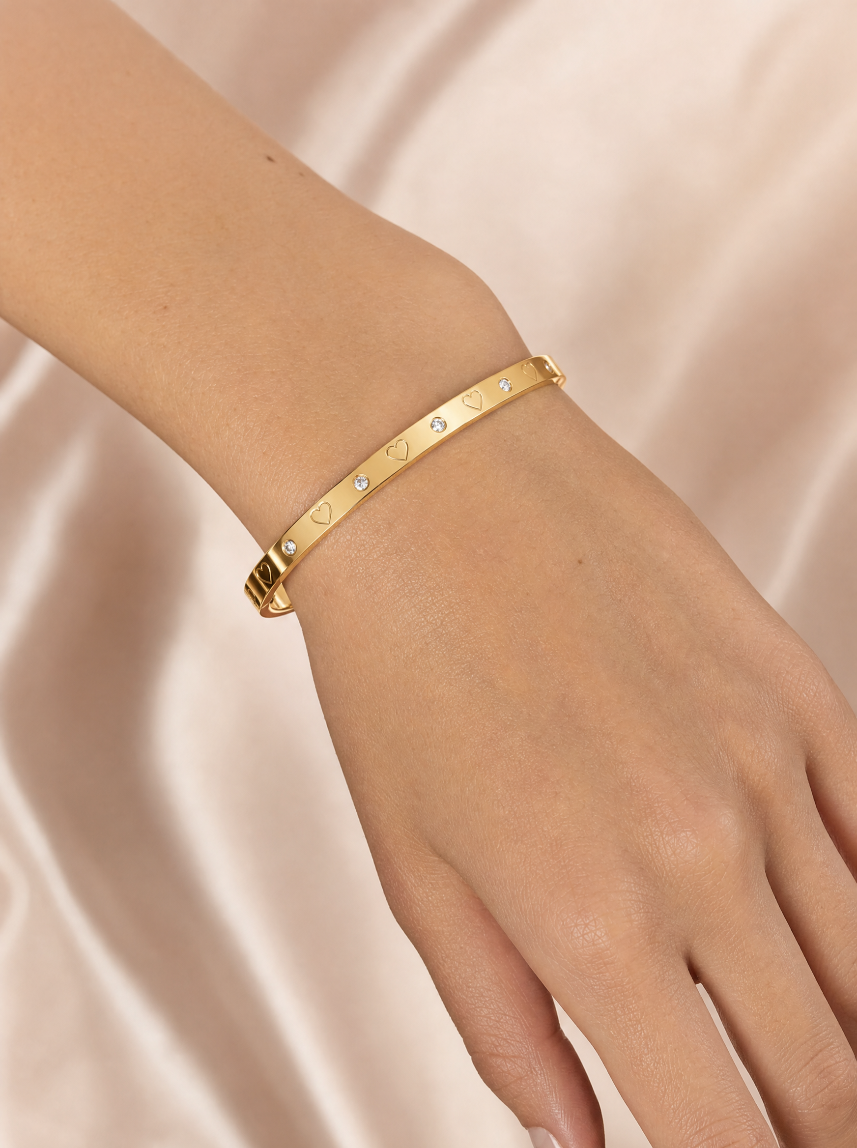 Woman wearing gold heart bangle with crystals