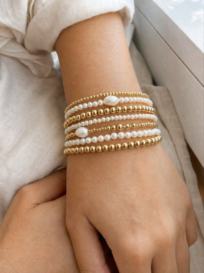 Woman wearing pearl and gold bead bracelet stack