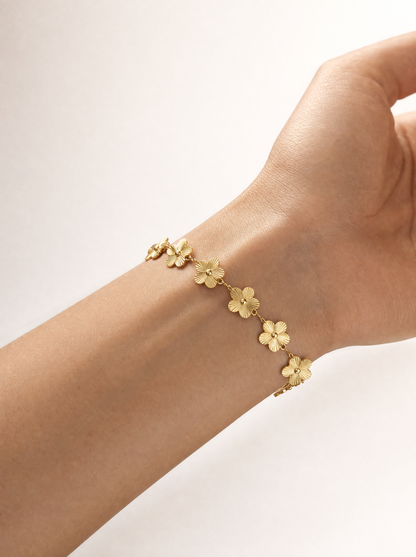 Woman wearing gold five-petal flower chain bracelet