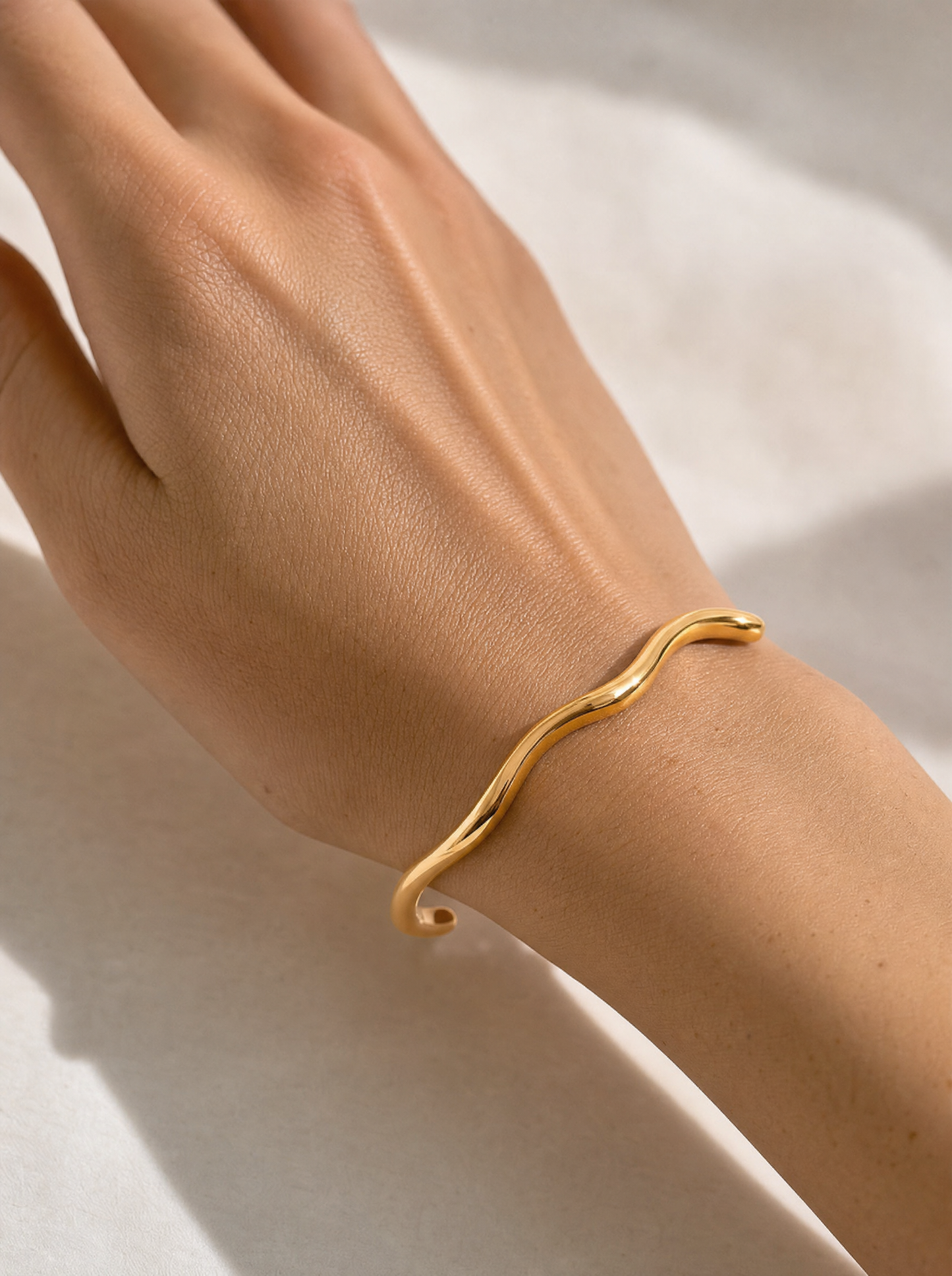 Wavy open cuff bracelet, 18K gold plated, on-wrist detail angle
