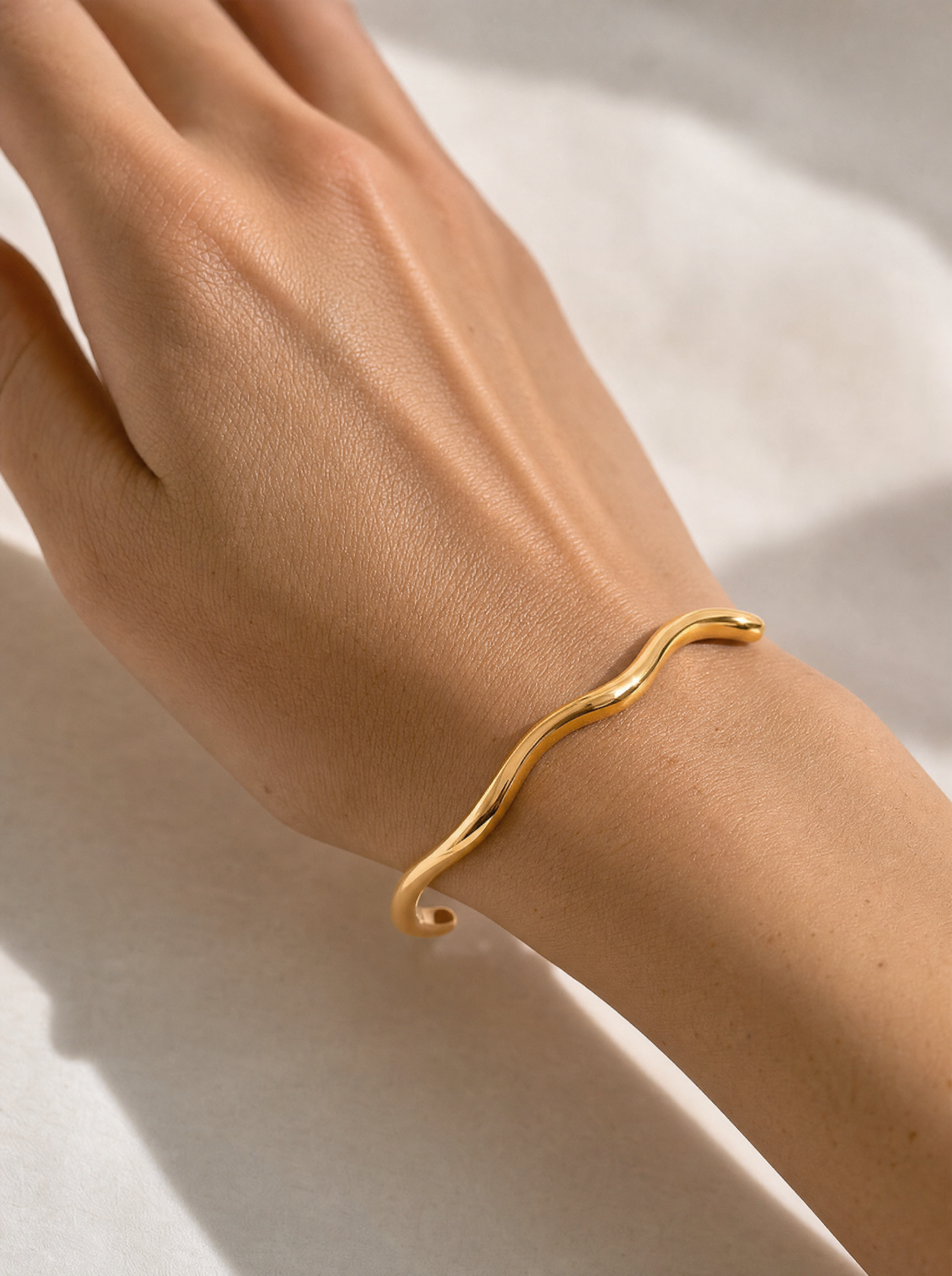 Wavy open cuff bracelet, 18K gold plated, on-wrist detail angle